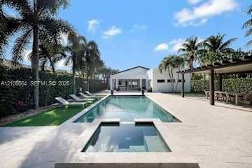 885 SW 144th Avenue, Miami, FL 33184 In-ground swimming pool with an attached spa, expansive stone paver pool deck, and timber-framed pergola