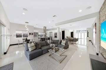 885 SW 144th Avenue, Miami, FL 33184 Open-concept interior featuring large-format tile flooring, recessed lighting, a stone-accent wall, and a kitchen island with built-in cabinetry