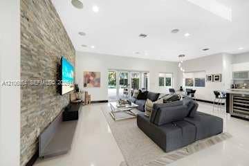 885 SW 144th Avenue, Miami, FL 33184 Open-concept living space featuring a floor-to-ceiling stone-veneer accent wall, large-format tile flooring, recessed lighting, and multi-panel sliding glass doors