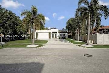 885 SW 144th Avenue, Miami, FL 33184 Single-story exterior featuring a concrete driveway, two-car garage, manicured lawn, and mature palm trees