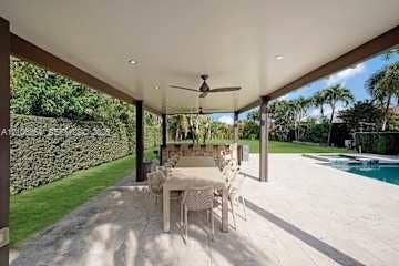 885 SW 144th Avenue, Miami, FL 33184 Covered patio featuring recessed lighting, a ceiling fan, an outdoor kitchen with stone veneer base, and a stone-paver deck overlooking a pool