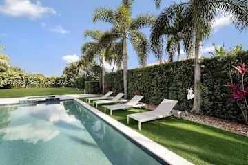 885 SW 144th Avenue, Miami, FL 33184 In-ground swimming pool with a light-toned interior, bordered by a synthetic turf lawn, tall privacy hedge, and mature palm trees