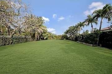 885 SW 144th Avenue, Miami, FL 33184 Expansive grounds featuring a manicured lawn, perimeter hedge fencing, and mature palm trees