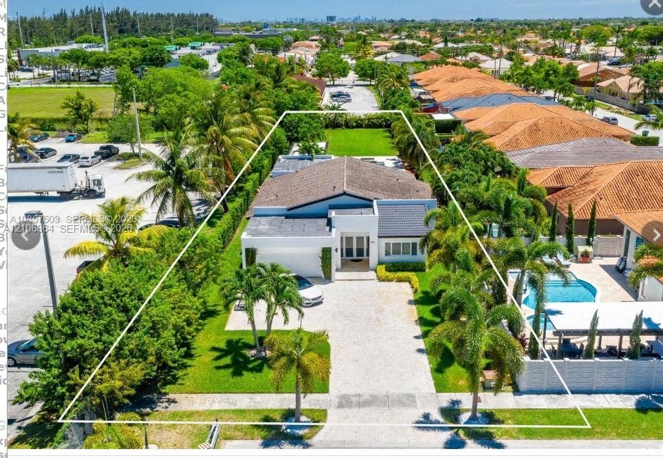 885 SW 144th Avenue, Miami, FL 33184 Aerial perspective featuring a residential property with a paved driveway, manicured lawn, mature palm trees, and an in-ground swimming pool