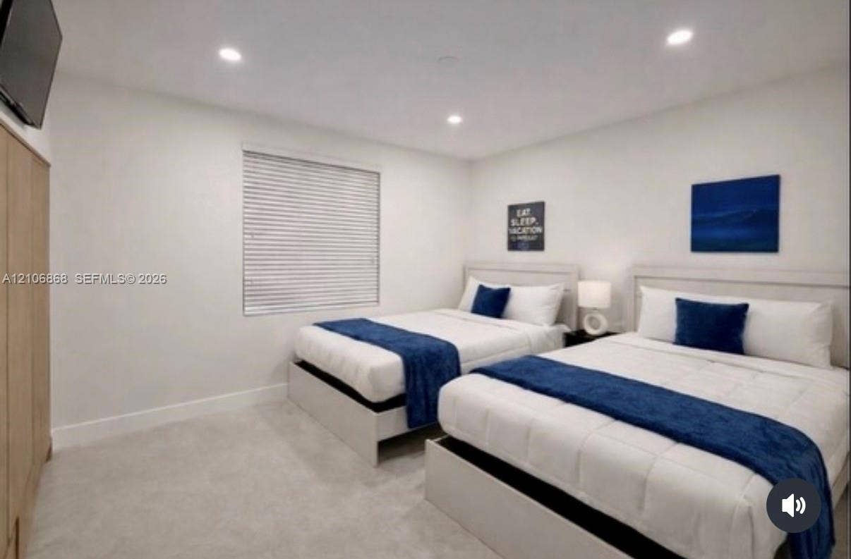 Neutral-toned carpeting, recessed lighting, and a window with horizontal blinds