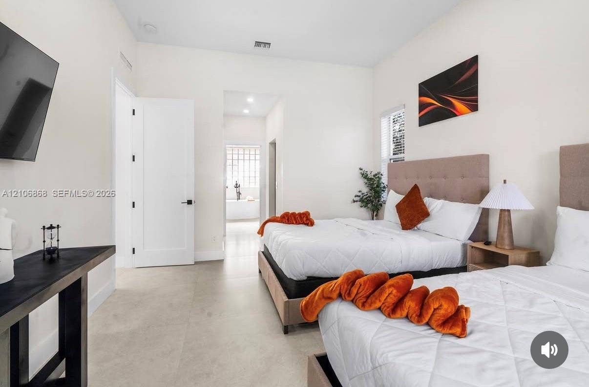 Light-filled room featuring neutral tile flooring, crisp white walls, high ceilings, and solid-core doors with matte black hardware