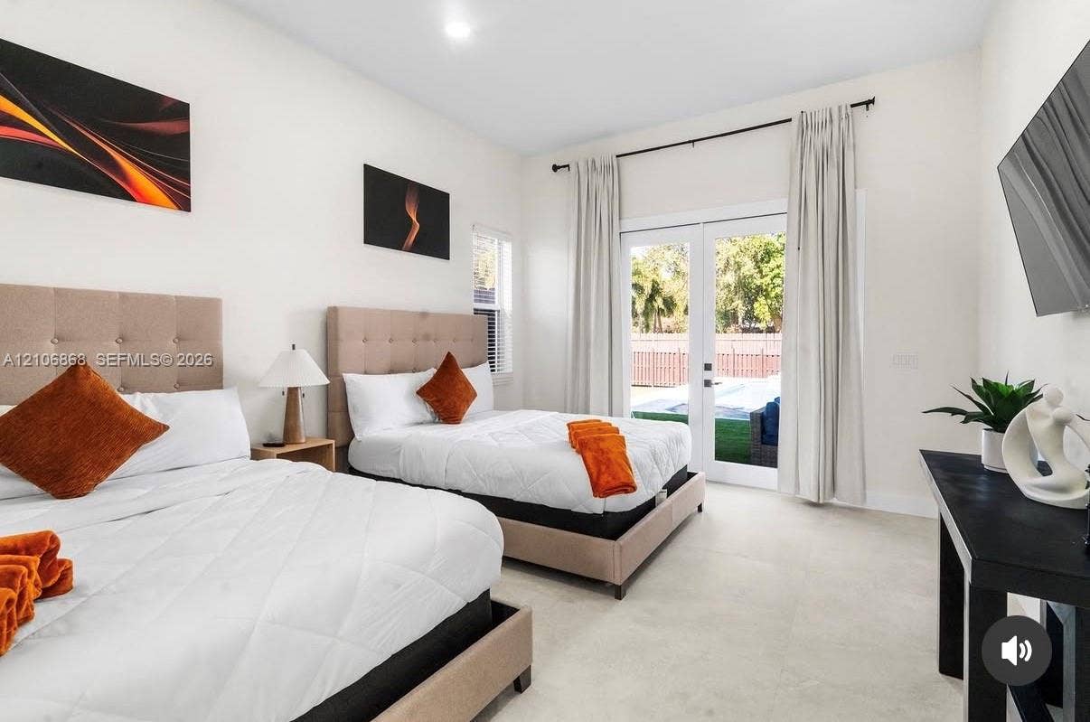 Light-filled space featuring large-format tile flooring, high ceilings, and double glass-paned doors with exterior access