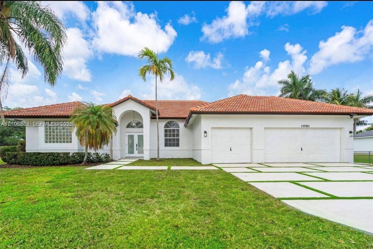 Single-story residence featuring a terracotta-tiled roof, white stucco exterior, arched entryway, arched transom windows, and a multi-car garage