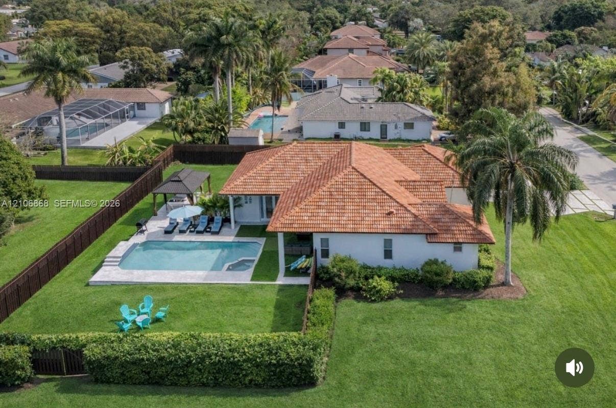 Single-story residence featuring a clay tile roof, an inground swimming pool with a stone paver deck, a detached gazebo, and expansive manicured lawn space enclosed by a privacy fence