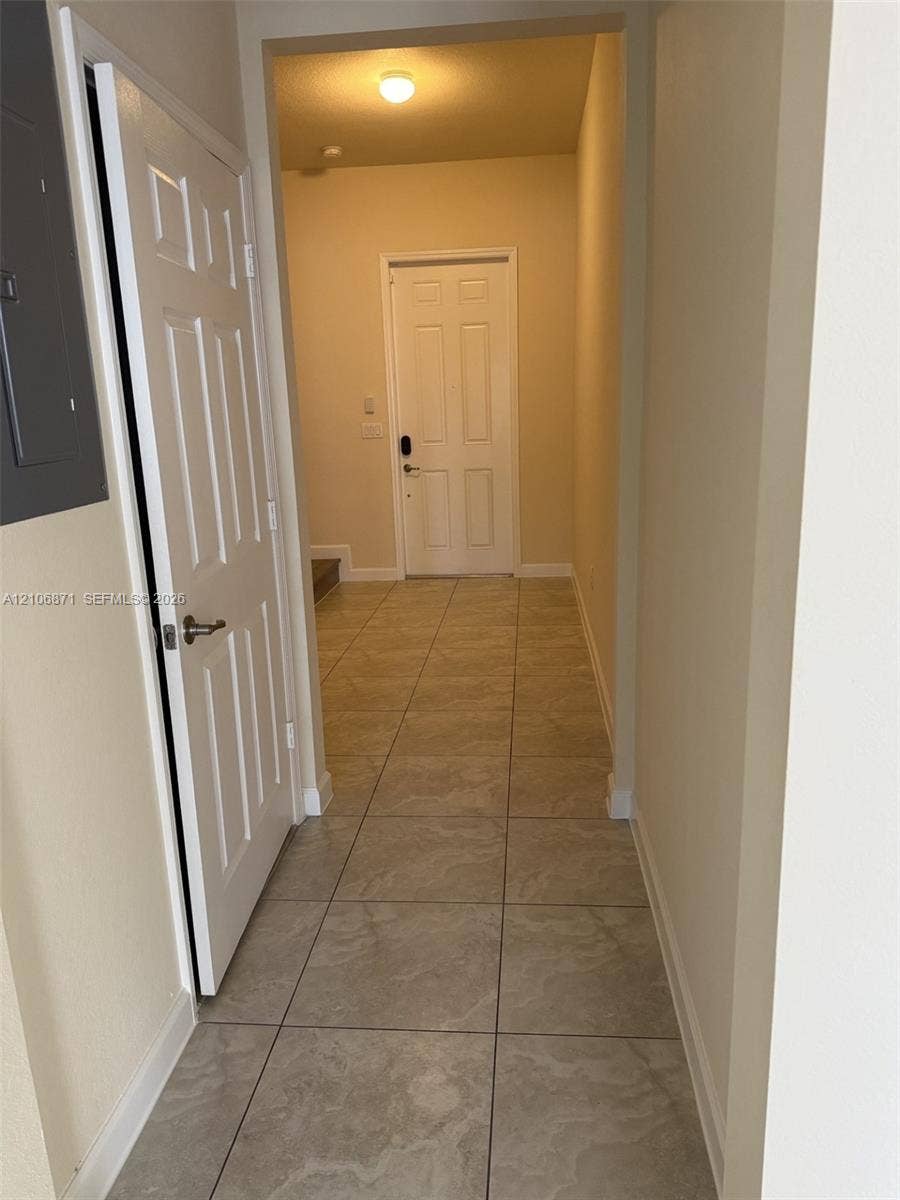 Neutral tile flooring featuring large-format stone-patterned tiles, six-panel interior doors, and a ceiling-mounted light fixture