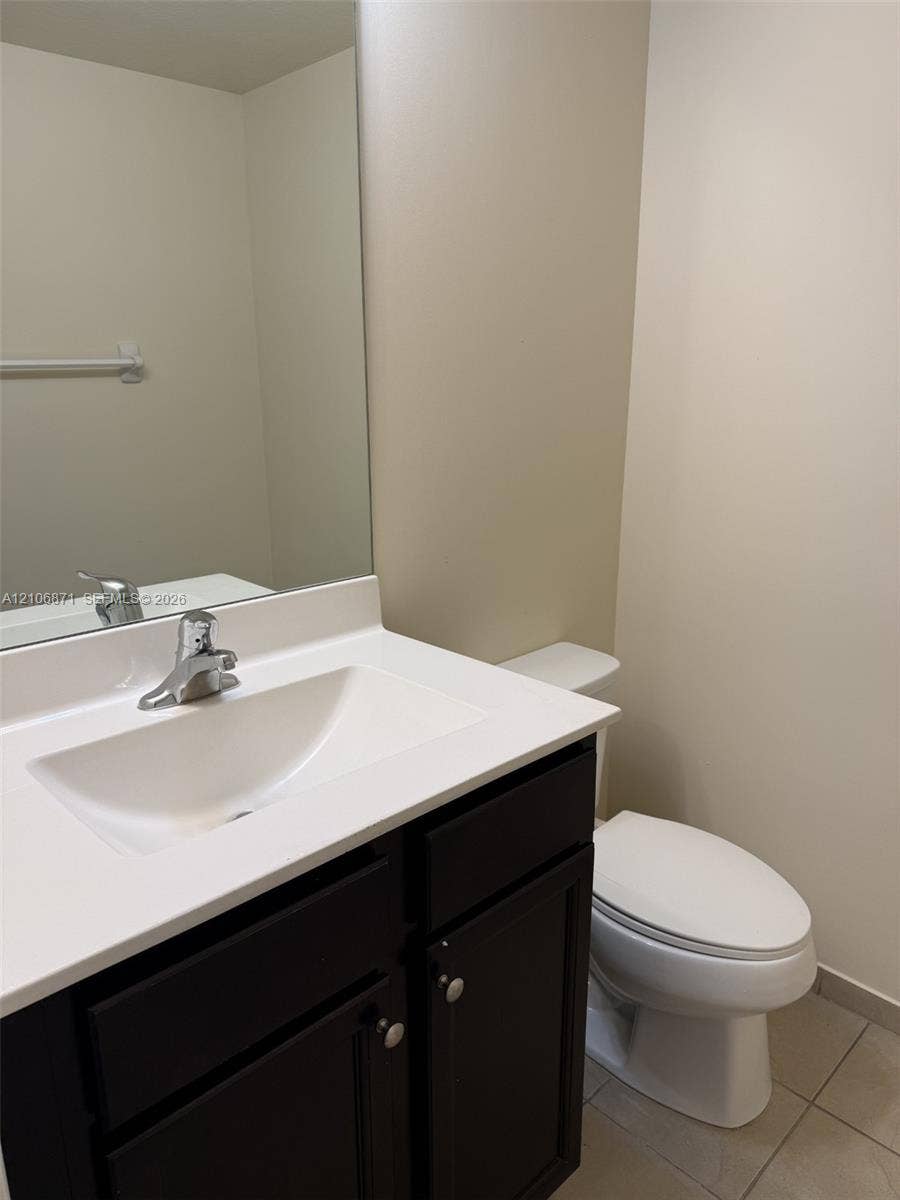 Vanity featuring a dark-finish cabinet, solid-surface countertop, integrated rectangular sink, chrome-finish faucet, and a wall-mounted mirror