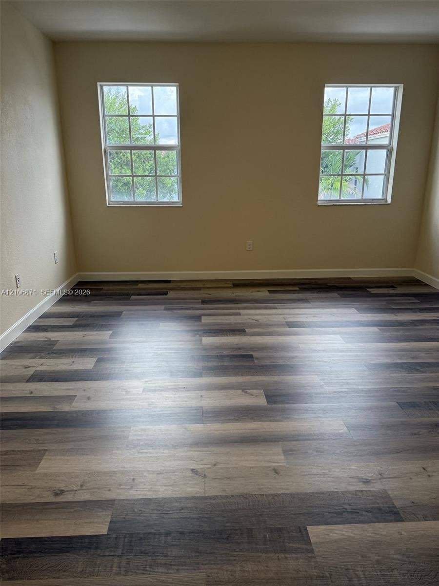 Multi-tone wood-finish flooring, two dual-pane windows with grid detailing, and neutral wall color