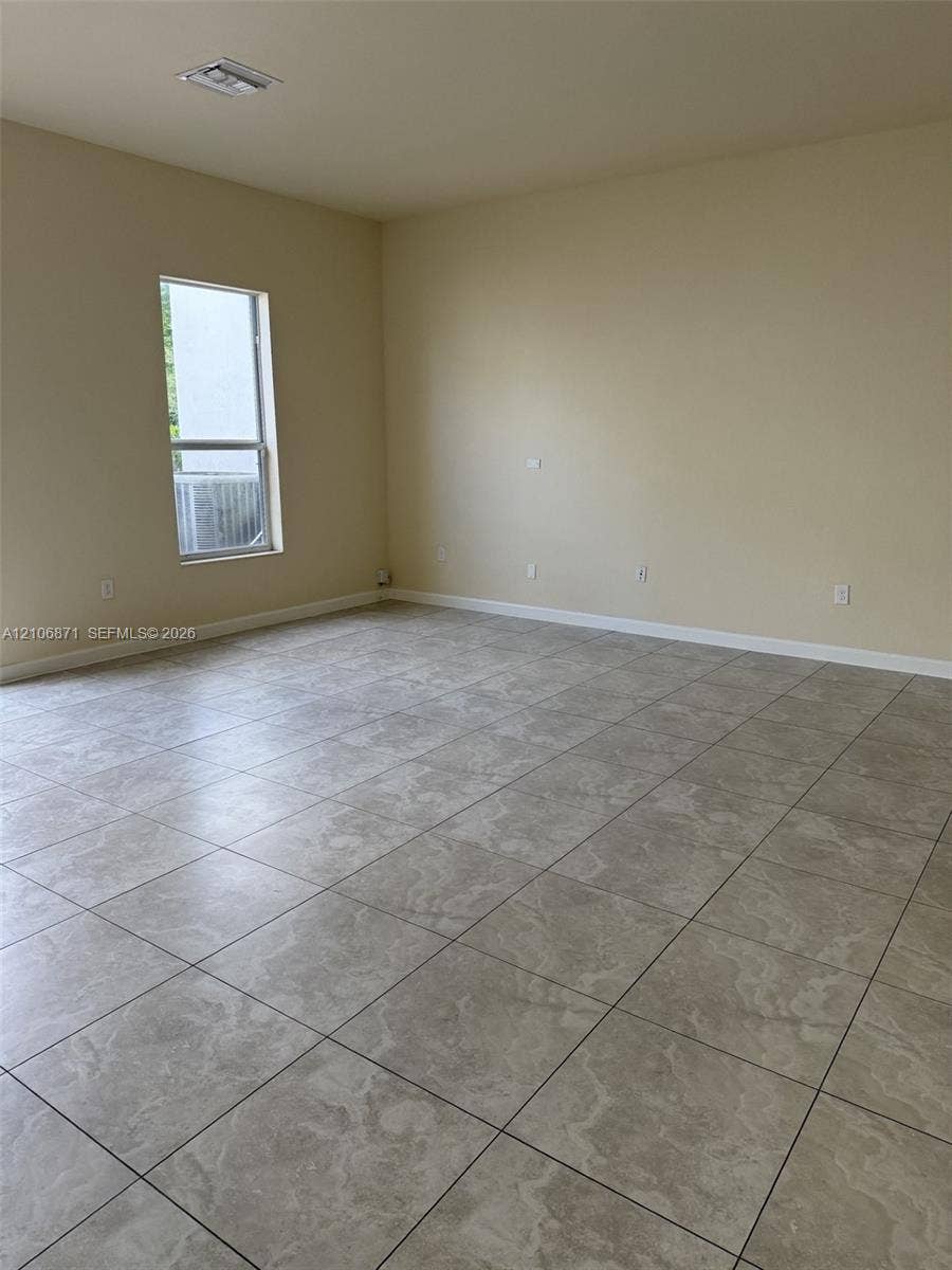 Neutral-toned interior space featuring large-format tile flooring and a vertical window