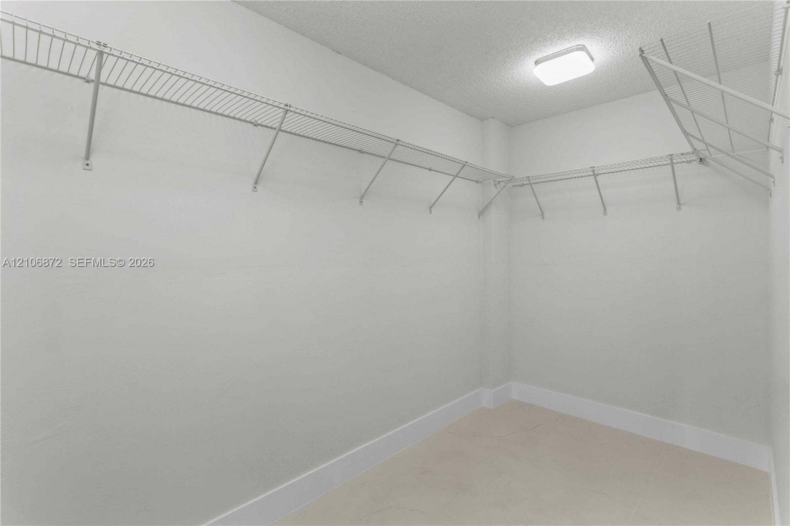Walk-in storage space featuring neutral walls, ceiling-mounted lighting, and integrated wire shelving
