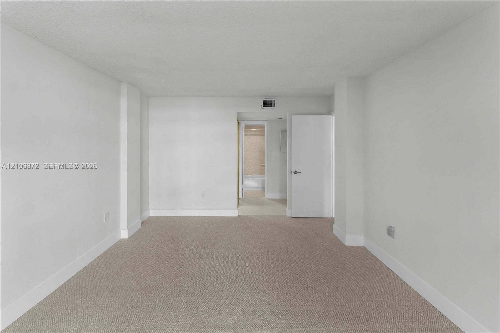 Neutral-toned carpeting, smooth-finish walls, and a solid-core interior door