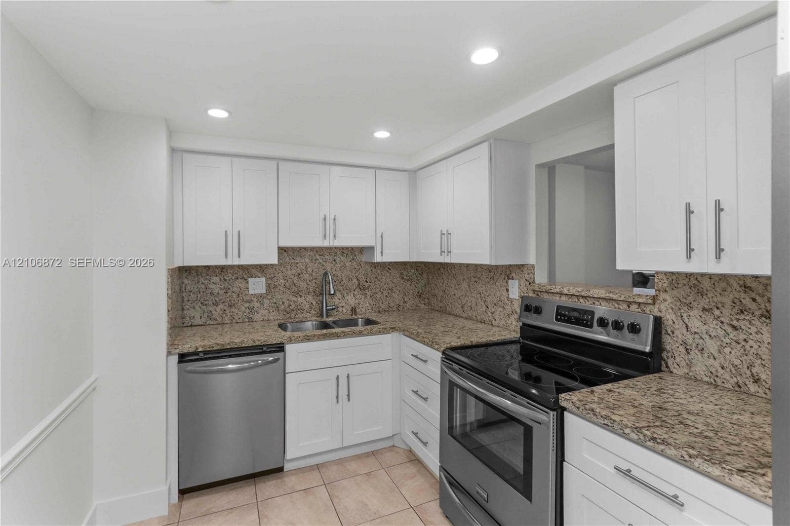 Kitchen featuring white Shaker-style cabinetry, stone countertops, stainless steel appliances, recessed lighting, and tile flooring