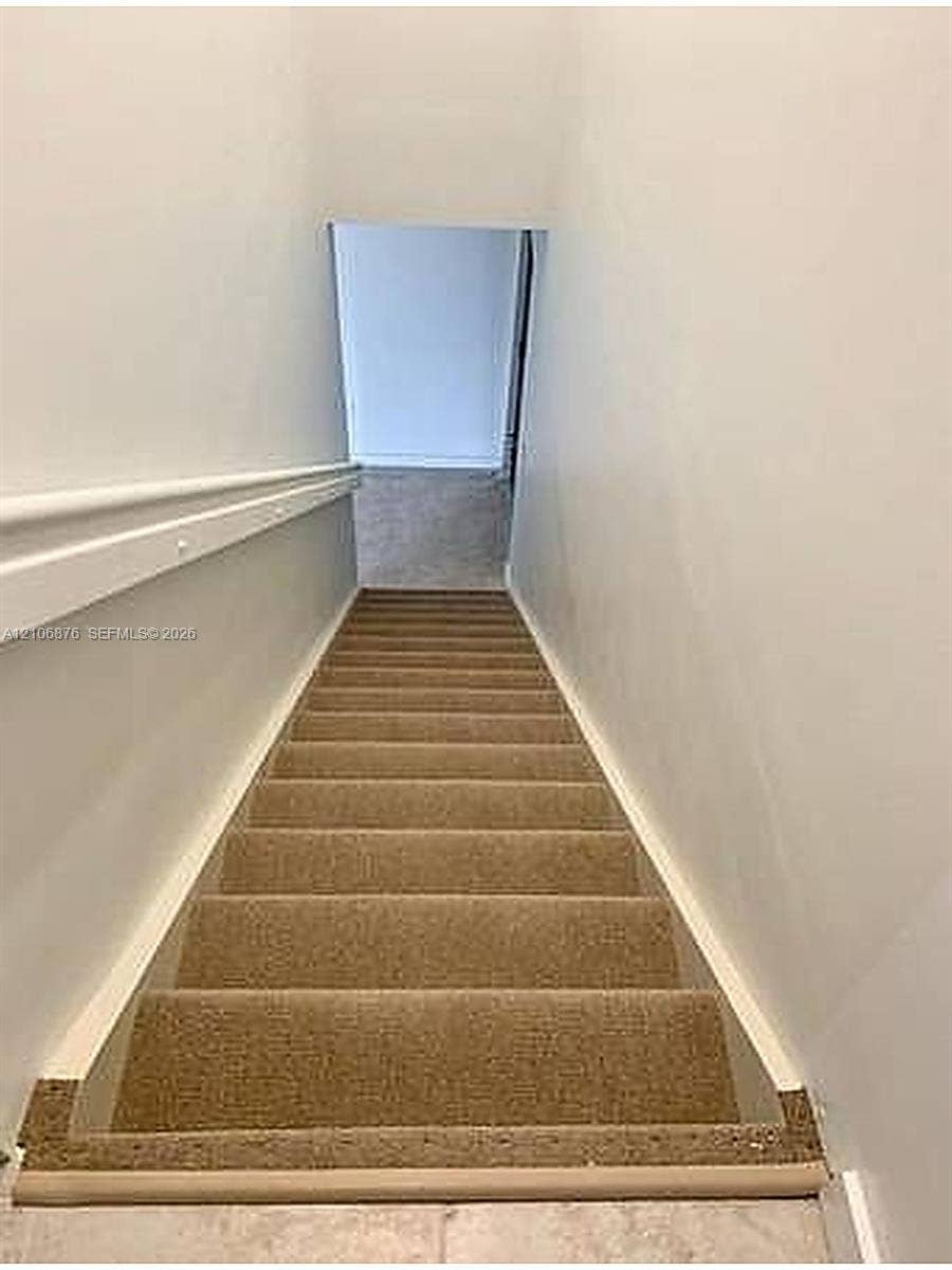 Staircase featuring wall-to-wall carpeting and a fixed handrail