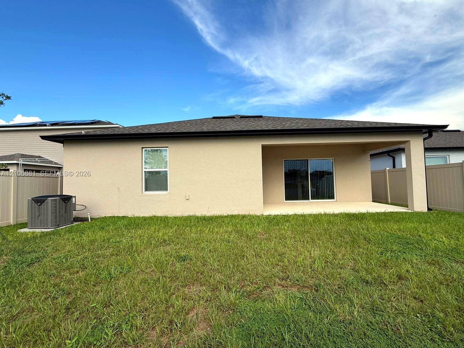 Rear exterior featuring a covered patio, stucco siding, shingle roof, and vinyl privacy fencing