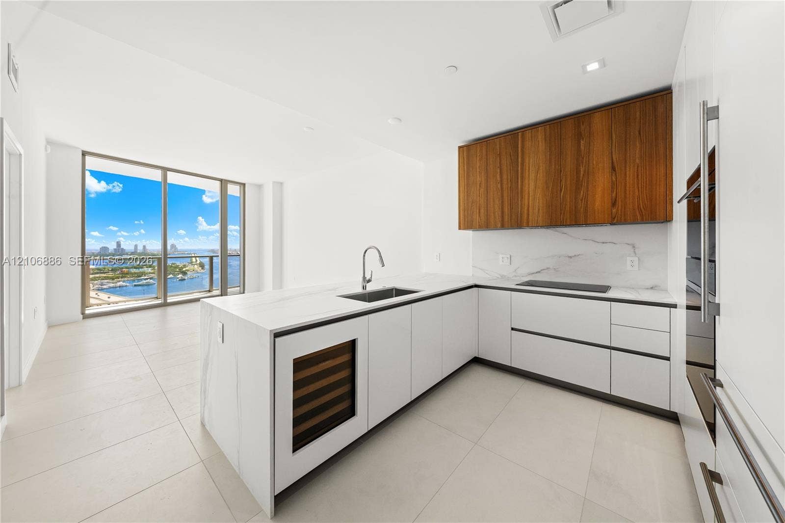 1400 Biscayne Boulevard, #2603, Miami, FL 33132 Modern kitchen featuring matte white cabinetry, wood-finish upper cabinetry, stone-surface countertops with matching backsplash, built-in wine refrigeration, and floor-to-ceiling windows