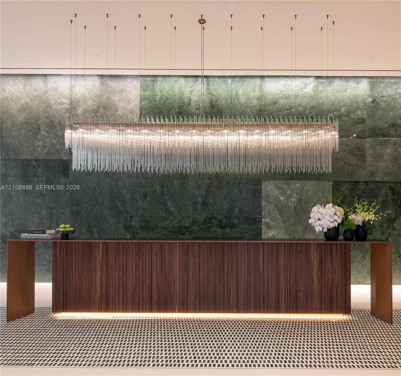 1400 Biscayne Boulevard, #2603, Miami, FL 33132 Large-scale linear chandelier with crystalline fringe, wood-veneer floating desk with base accent lighting, and full-height green-toned stone feature wall