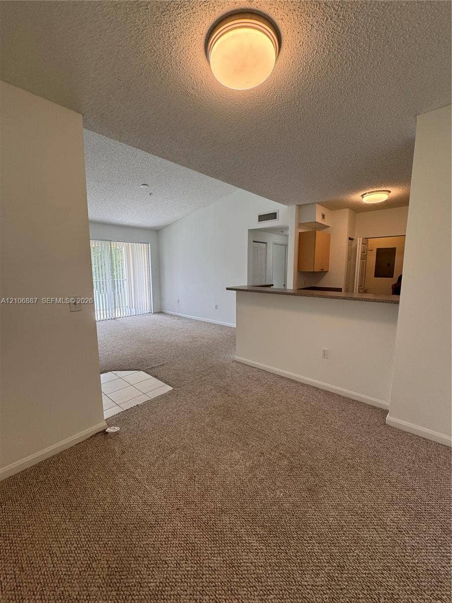 7950 N Nob Hill Road, #202, Tamarac, Tamarac, FL 33321 Interior featuring wall-to-wall carpeting, breakfast bar with countertop, sliding glass door, and flush-mount ceiling lighting