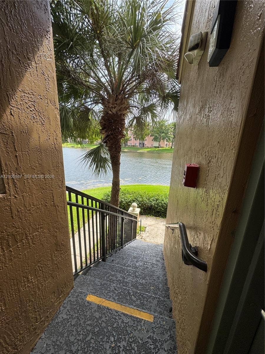 7950 N Nob Hill Road, #202, Tamarac, Tamarac, FL 33321 Exterior staircase featuring textured concrete steps, black metal handrails, and a water-facing orientation
