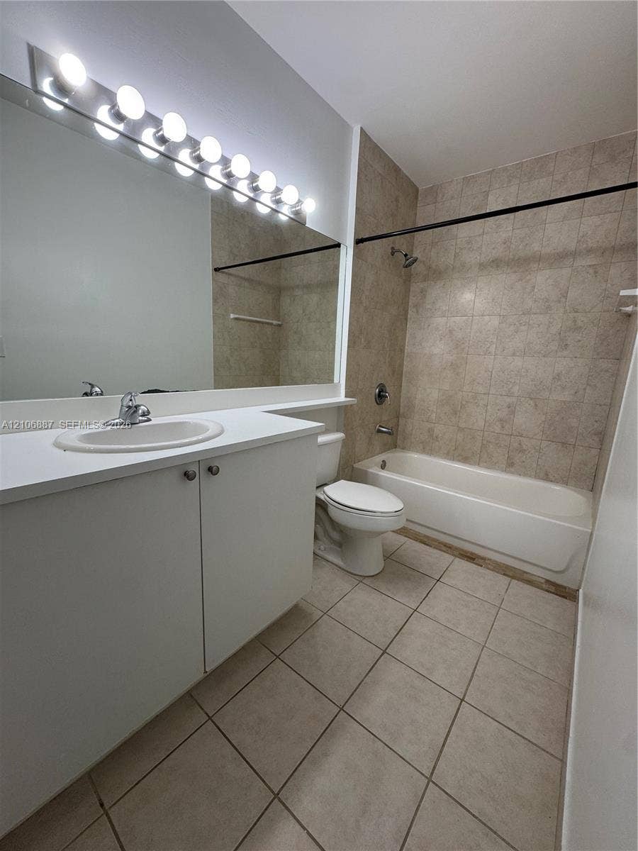 7950 N Nob Hill Road, #202, Tamarac, Tamarac, FL 33321 Bathroom featuring a vanity with white cabinetry, a neutral countertop, an integrated sink, a full-width wall mirror with integrated lighting, and a tub-shower combination with tile surround