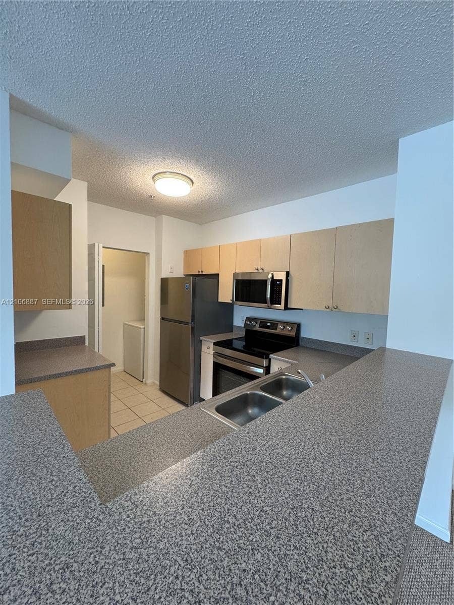 7950 N Nob Hill Road, #202, Tamarac, Tamarac, FL 33321 Kitchen featuring light-finish cabinetry, speckled countertops, stainless steel appliances, and a dual-basin stainless steel sink