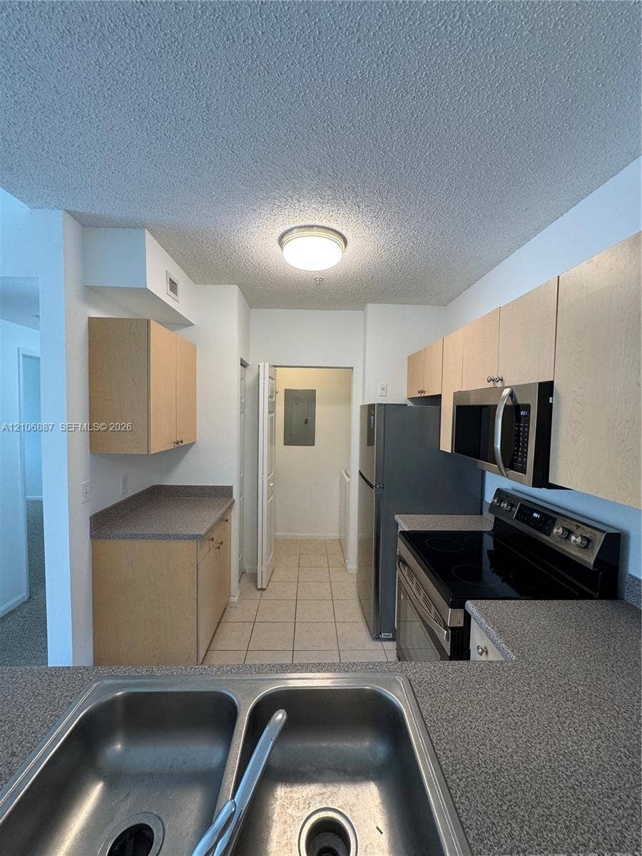 7950 N Nob Hill Road, #202, Tamarac, Tamarac, FL 33321 Kitchen featuring light-finish cabinetry, neutral solid-surface countertops, dual-basin stainless steel sink, and integrated microwave