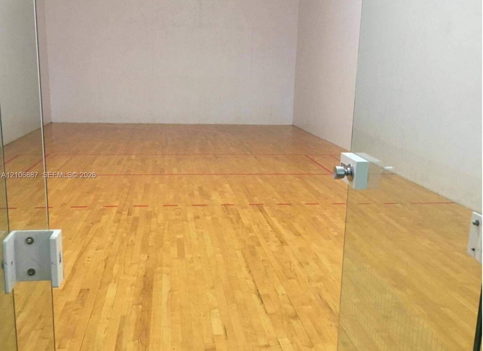7950 N Nob Hill Road, #202, Tamarac, Tamarac, FL 33321 Recreational court featuring wood-finish flooring, glass panel entryway, and high-clearance walls with court boundary markings