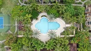 7950 N Nob Hill Road, #202, Tamarac, Tamarac, FL 33321 Aerial perspective of a common area featuring a swimming pool, paved deck, hard-surface tennis court, and lush landscaping with mature palm trees