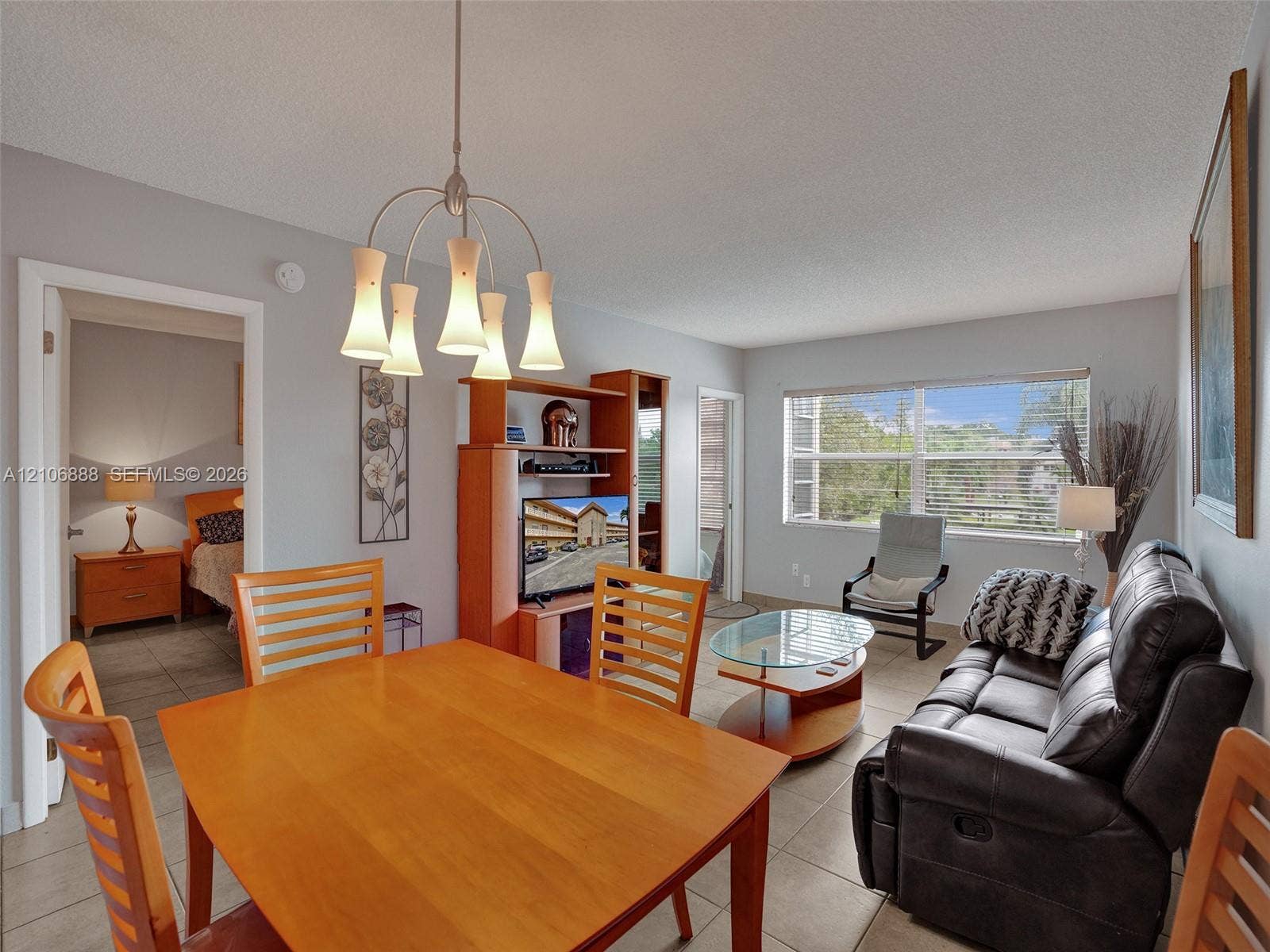 3506 NW 49th Avenue, #508, Lauderdale Lakes, FL 33319 Open-concept living and dining area featuring neutral wall paint, tile flooring, and a multi-light brushed-metal chandelier