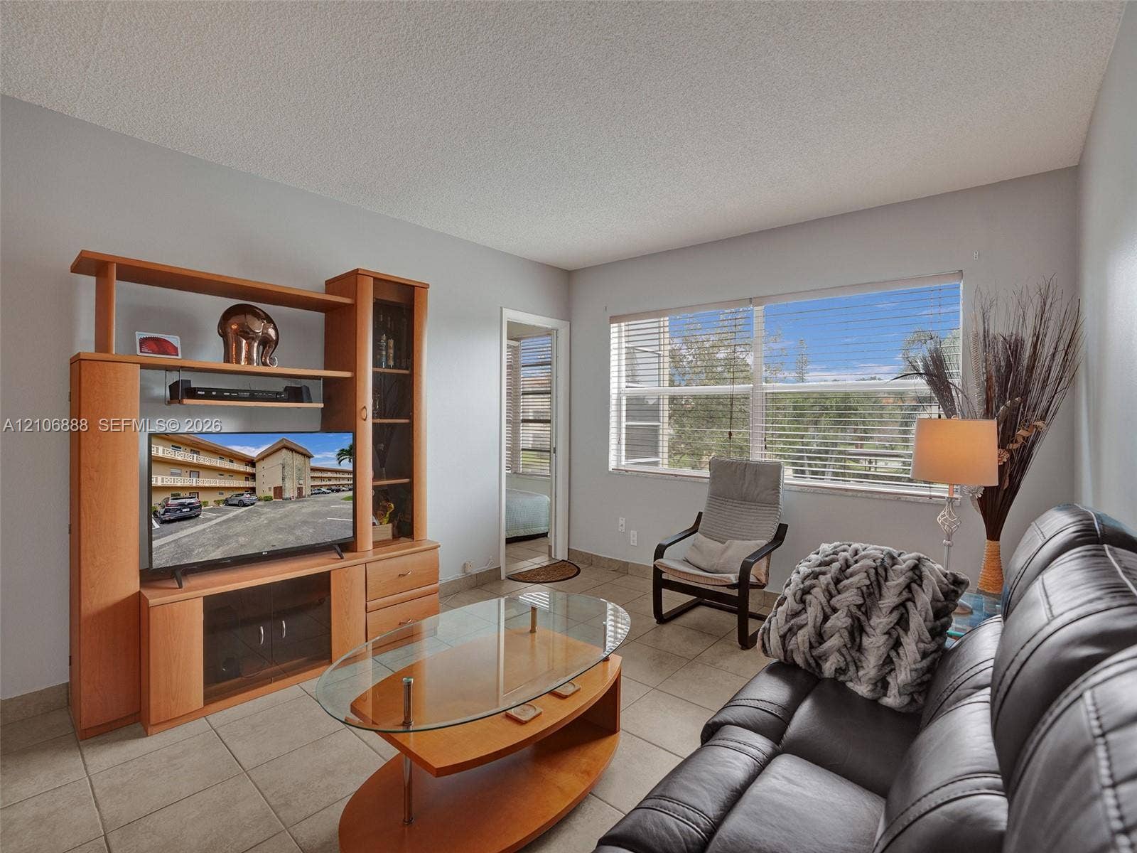 3506 NW 49th Avenue, #508, Lauderdale Lakes, FL 33319 Living area featuring large format ceramic tile flooring and a wide window with horizontal blinds