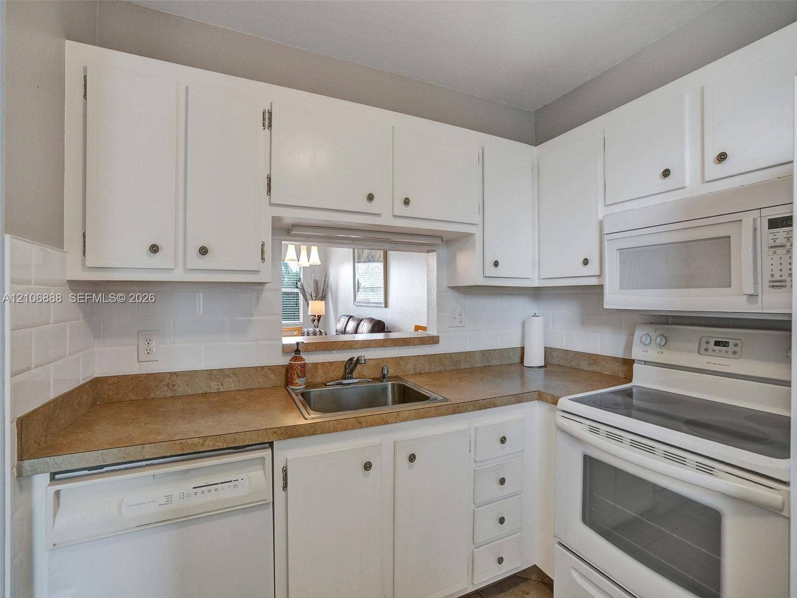 3506 NW 49th Avenue, #508, Lauderdale Lakes, FL 33319 Kitchen featuring white shaker-style cabinetry, white subway tile backsplash, solid-surface countertops, an undermount stainless steel sink, and built-in appliances