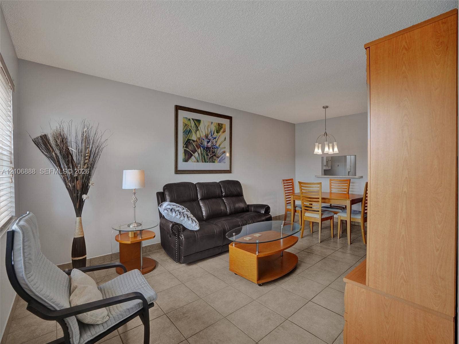 3506 NW 49th Avenue, #508, Lauderdale Lakes, FL 33319 Neutral-toned interior space featuring ceramic tile flooring, a multi-light pendant fixture, and large-format windows with blinds
