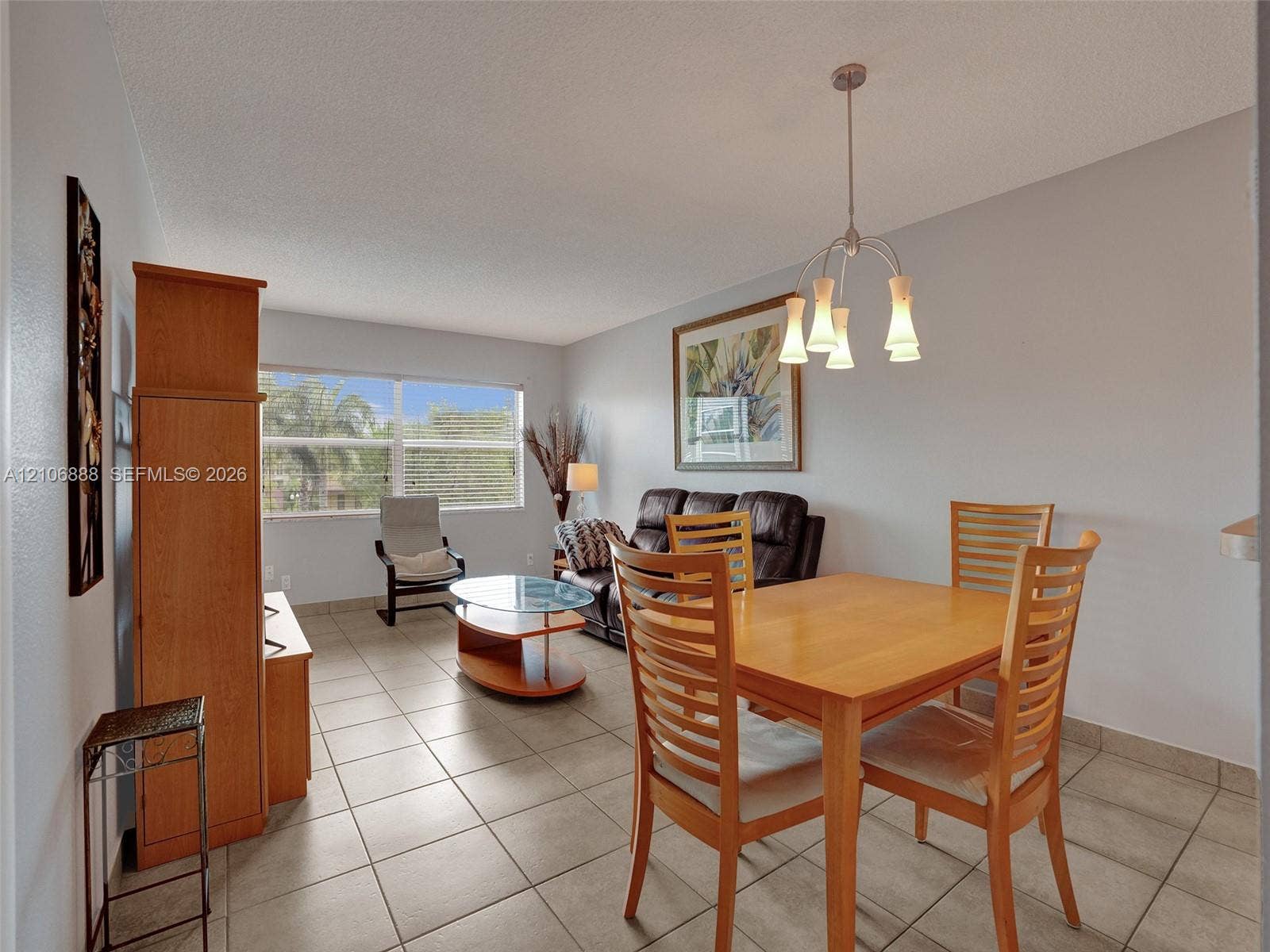 3506 NW 49th Avenue, #508, Lauderdale Lakes, FL 33319 Neutral-toned ceramic tile flooring, multi-arm metal pendant lighting, and large window with horizontal blinds