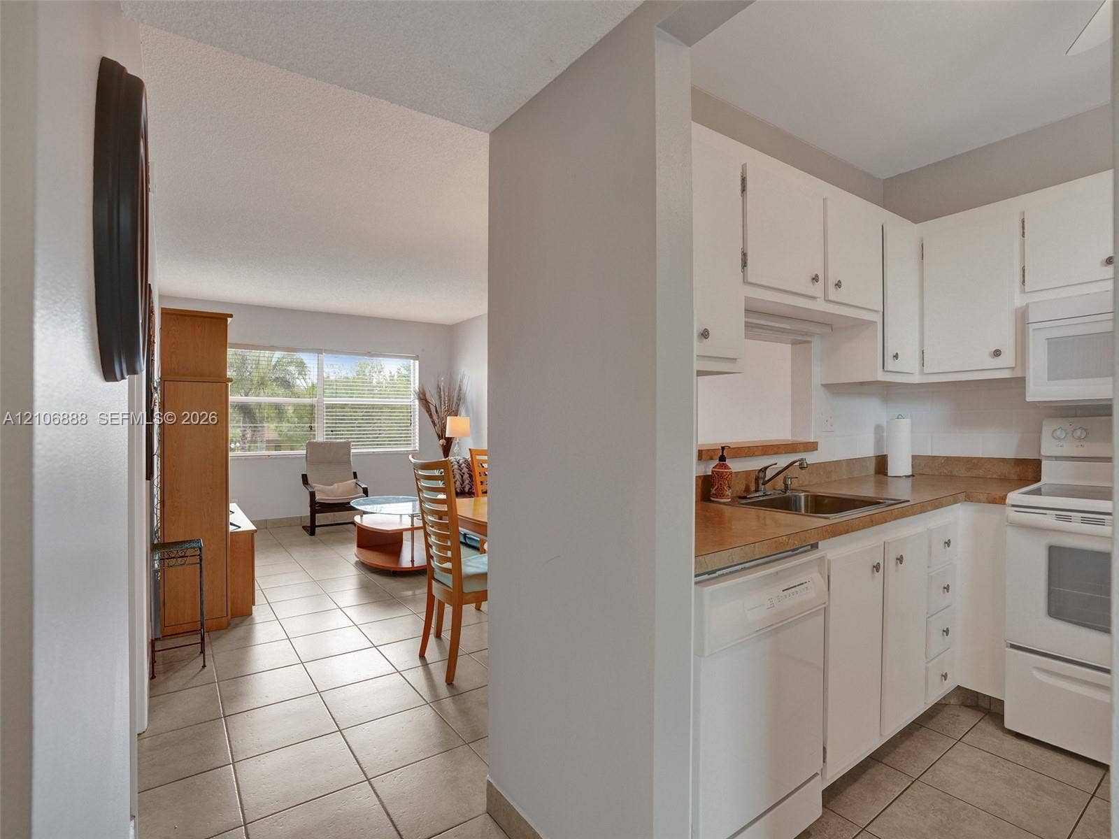 3506 NW 49th Avenue, #508, Lauderdale Lakes, FL 33319 Kitchen featuring white cabinetry, neutral-toned countertops, tile flooring, and integrated white appliances