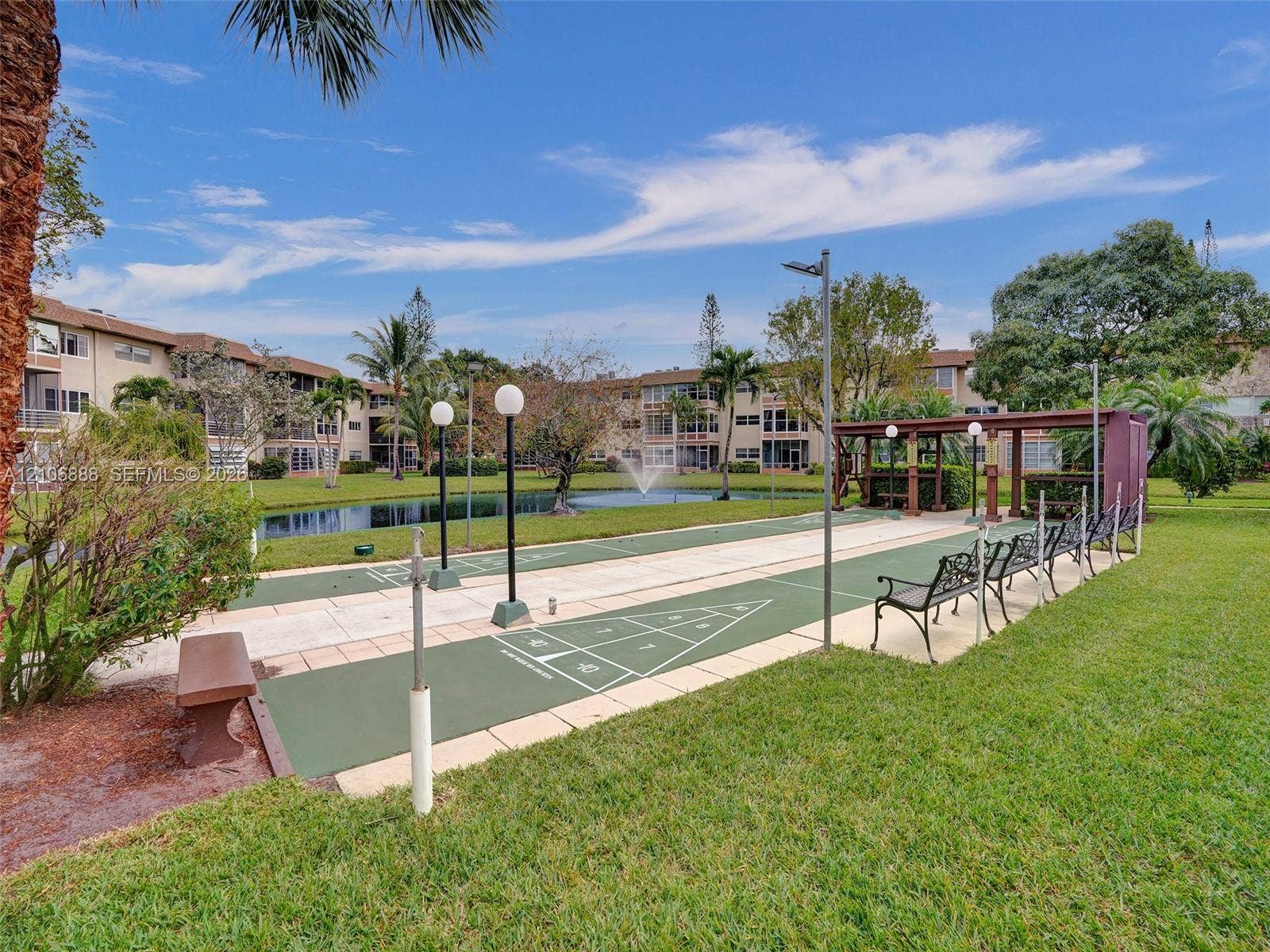 3506 NW 49th Avenue, #508, Lauderdale Lakes, FL 33319 Outdoor recreation area featuring a shuffleboard court, pergola, pond with fountain, and manicured green space
