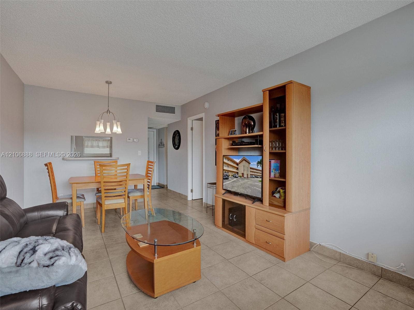 3506 NW 49th Avenue, #508, Lauderdale Lakes, FL 33319 Open-concept interior featuring neutral tile flooring, light-toned wall paint, and a built-in wooden media console
