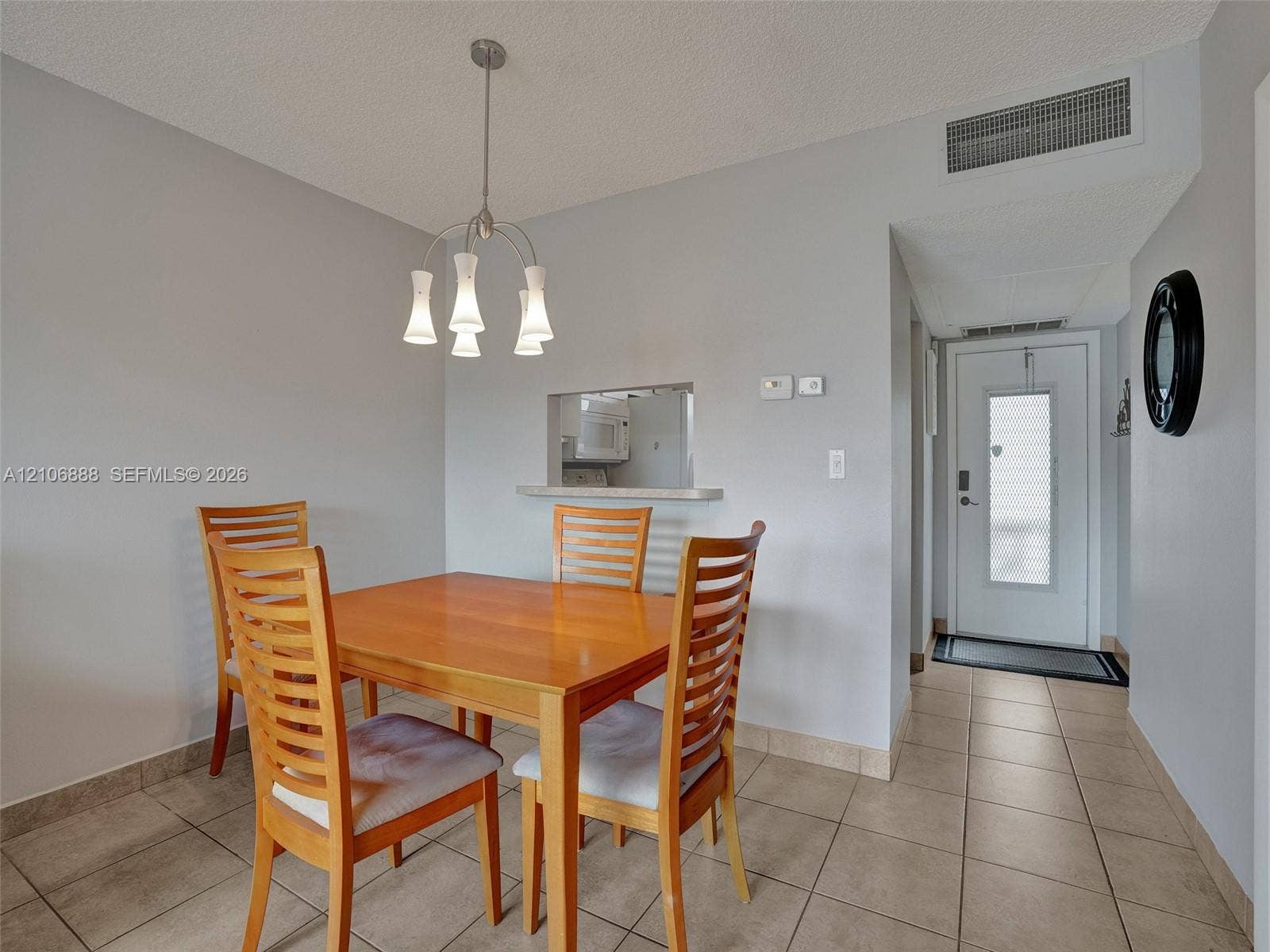 3506 NW 49th Avenue, #508, Lauderdale Lakes, FL 33319 Ceramic tile flooring, pass-through opening to kitchen, multi-light metal pendant fixture, and entry door with glass insert