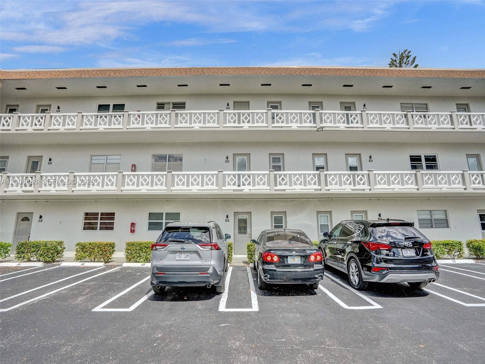 3506 NW 49th Avenue, #508, Lauderdale Lakes, FL 33319 Multi-story building exterior featuring white stucco facade, decorative lattice railings, and private balconies with individual entries