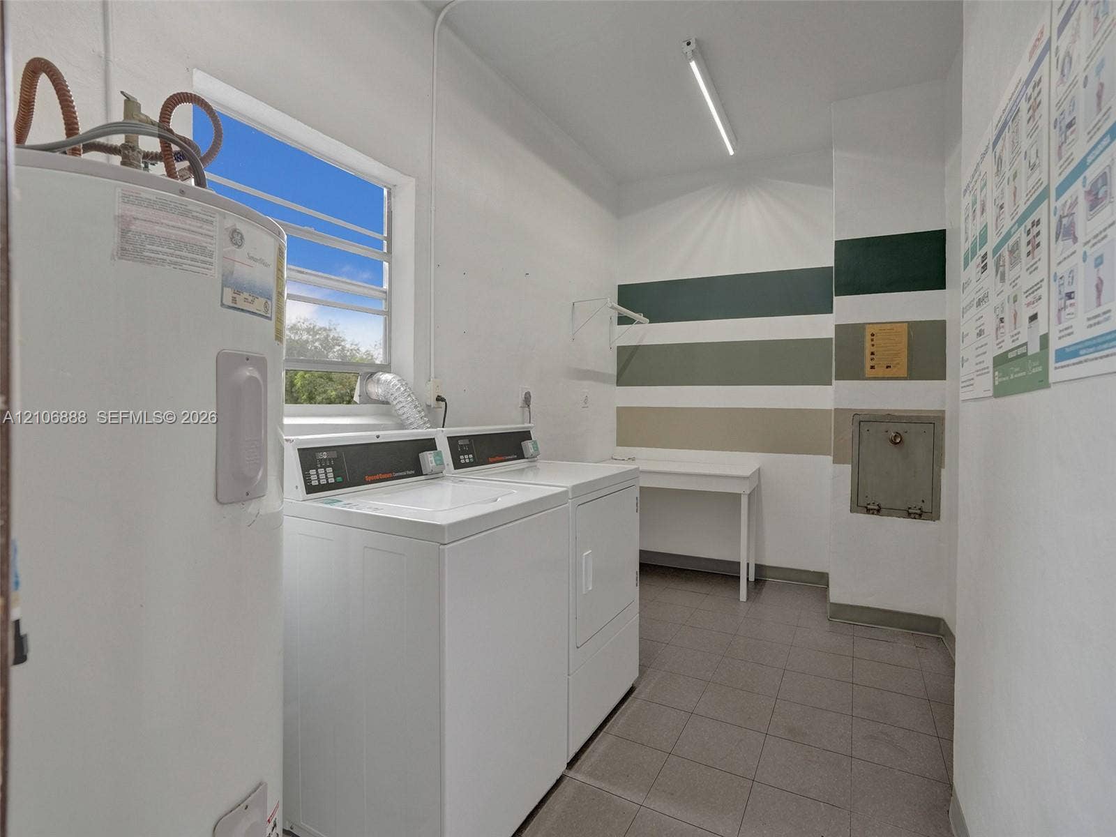 3506 NW 49th Avenue, #508, Lauderdale Lakes, FL 33319 Utility area featuring tile flooring, a water heater, a built-in folding surface, and an exterior-facing window