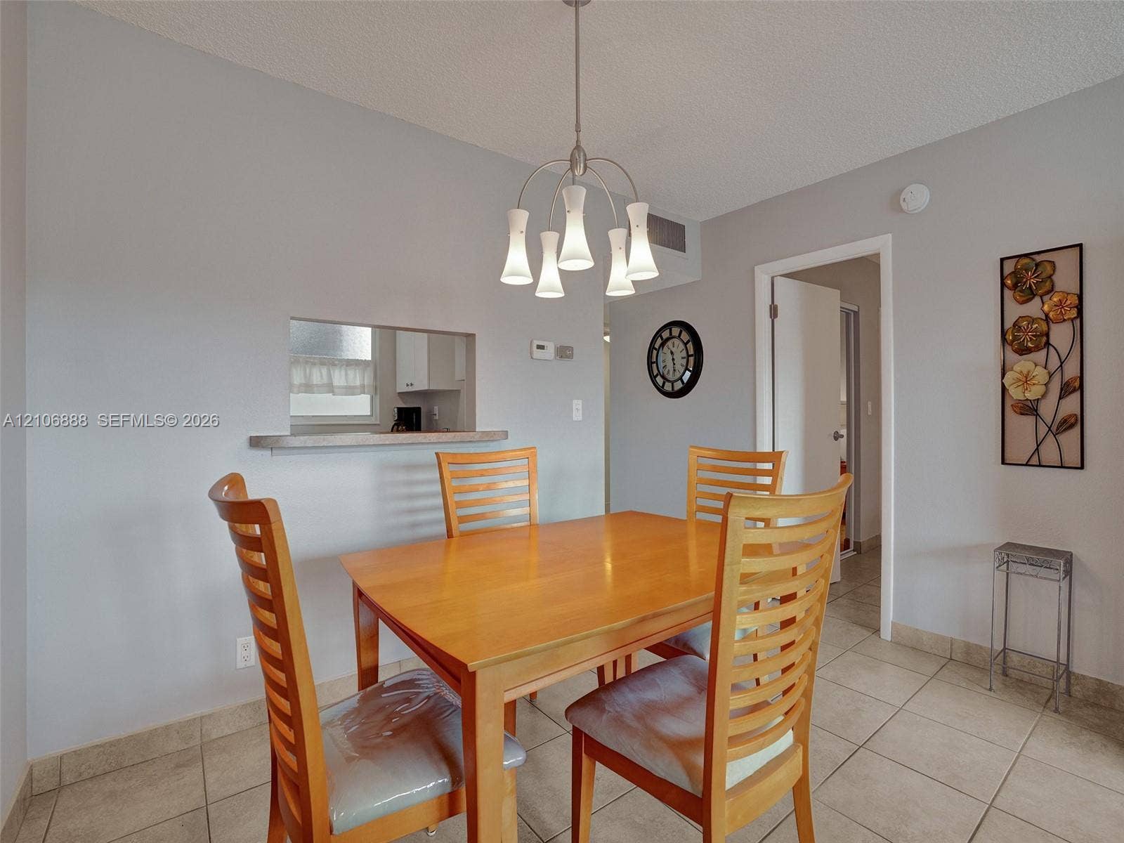 3506 NW 49th Avenue, #508, Lauderdale Lakes, FL 33319 Dining area featuring neutral wall paint, tile flooring, a multi-arm pendant light fixture, and a pass-through opening