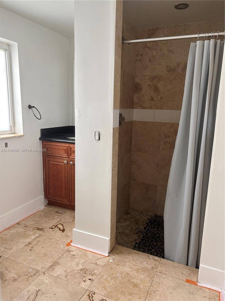 1322 N 31st Road, Hollywood, Hollywood, FL 33021 Bathroom featuring tile flooring, wood-finish vanity with a dark countertop, and a walk-in shower with natural stone wall tiles and a pebble-stone floor