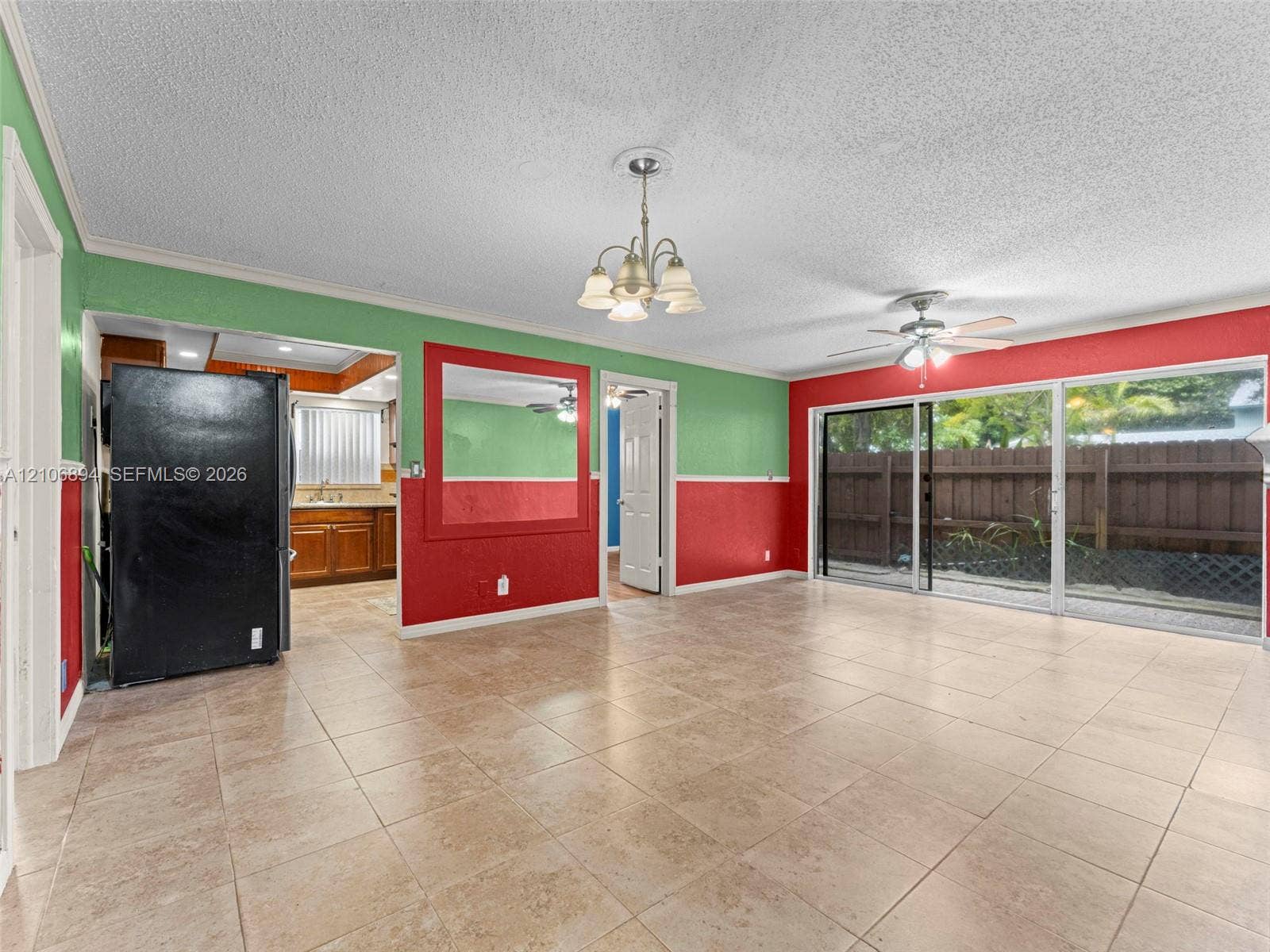 Large-format ceramic floor tiling, sliding glass patio doors, wall-mounted light fixture with frosted glass shades, and integrated ceiling fan with light kit