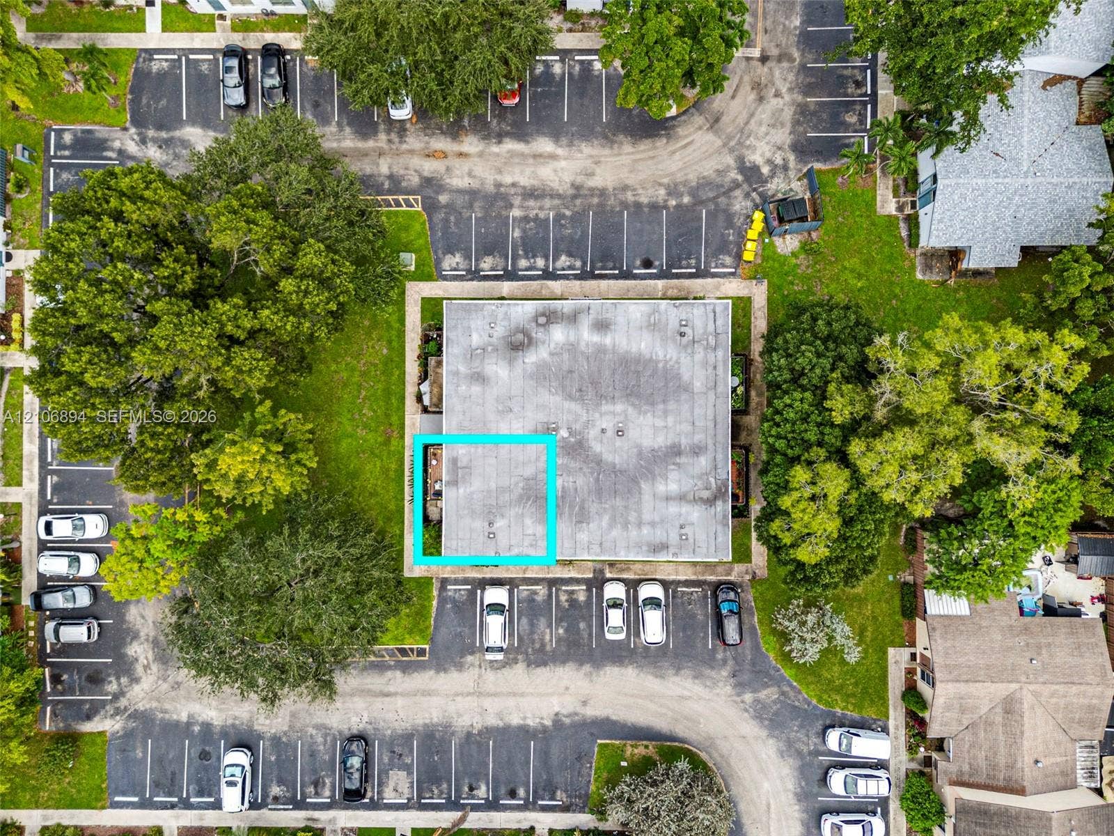Aerial perspective featuring designated asphalt parking spaces, mature landscaping, and green space surrounding the structure