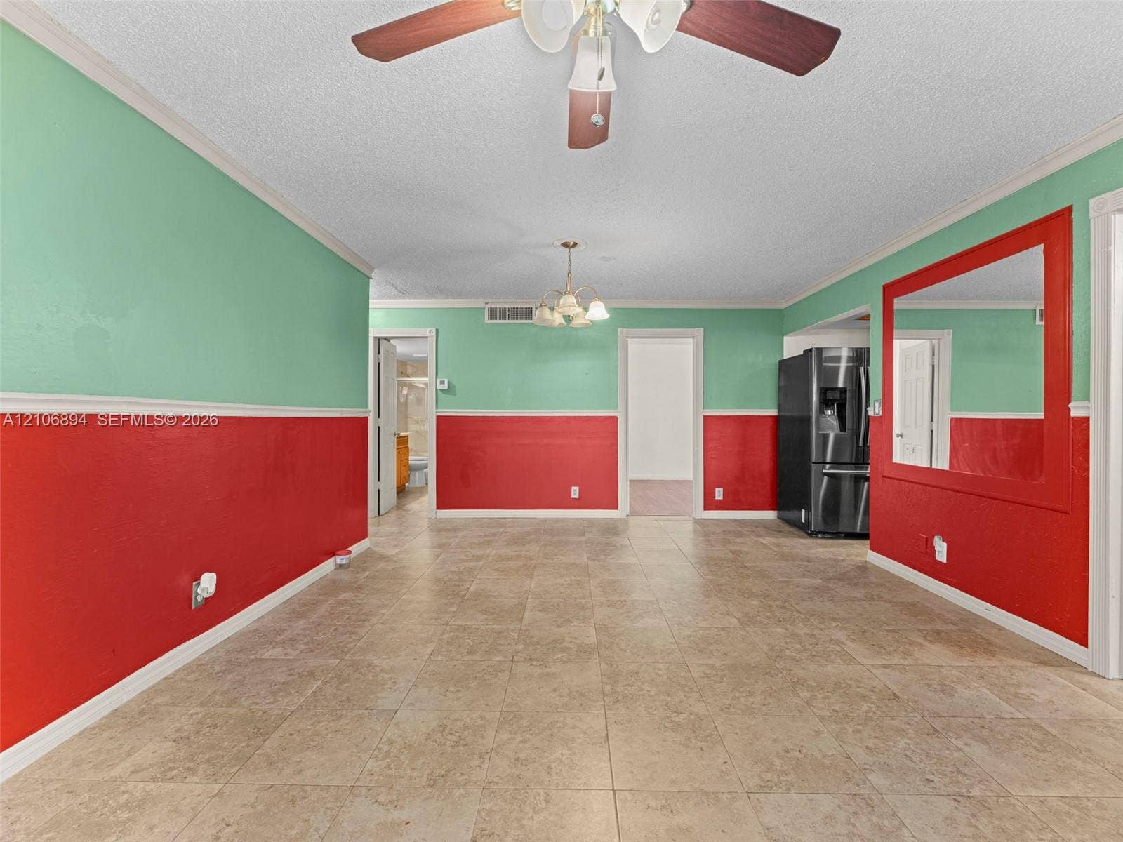 Interior space featuring ceramic tile flooring, a dual-tone wall treatment, a ceiling fan with light fixture, an integrated wall mirror, and a built-in multi-door refrigerator