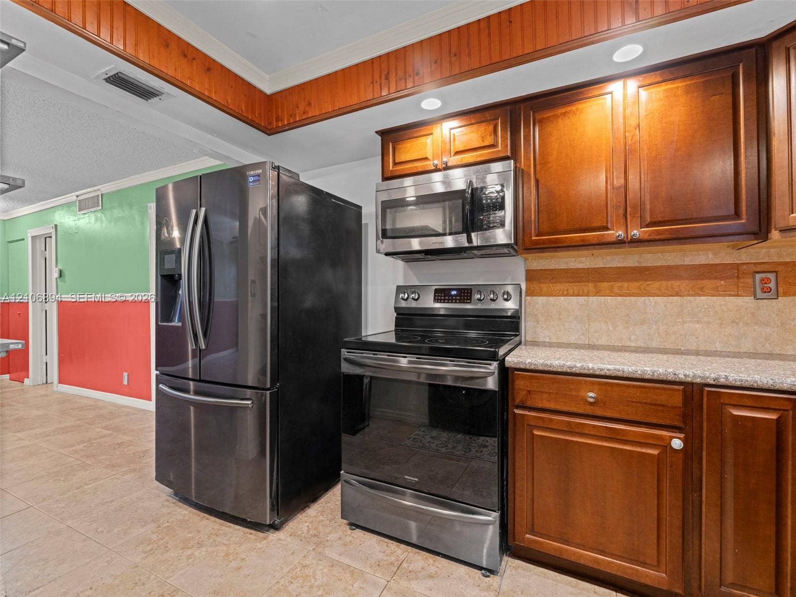 Kitchen featuring wood cabinetry, stainless steel appliances, speckled stone-surface countertops, recessed lighting, and tile flooring