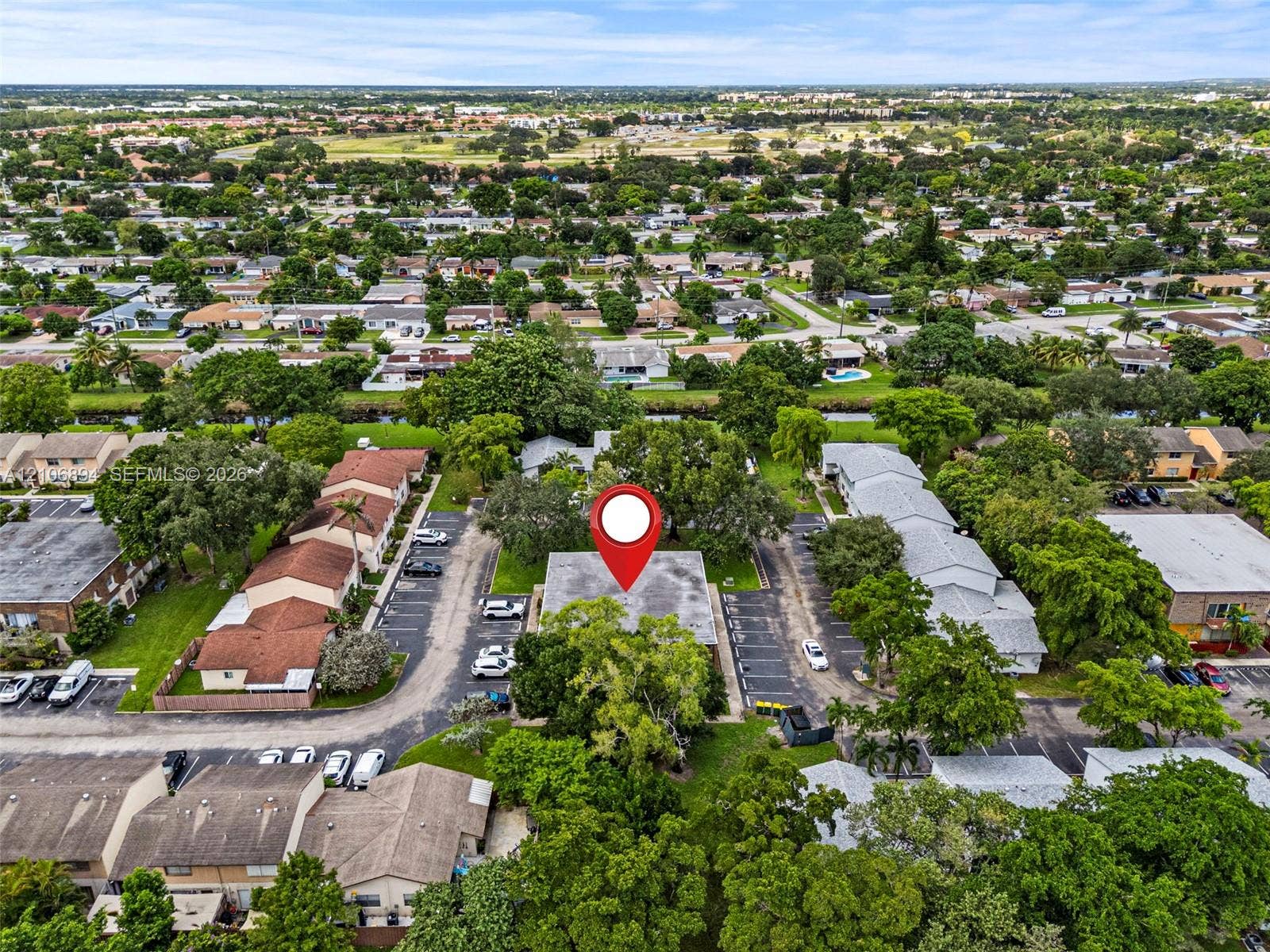 Aerial perspective featuring a multi-unit building structure with dedicated surface parking and mature landscaping