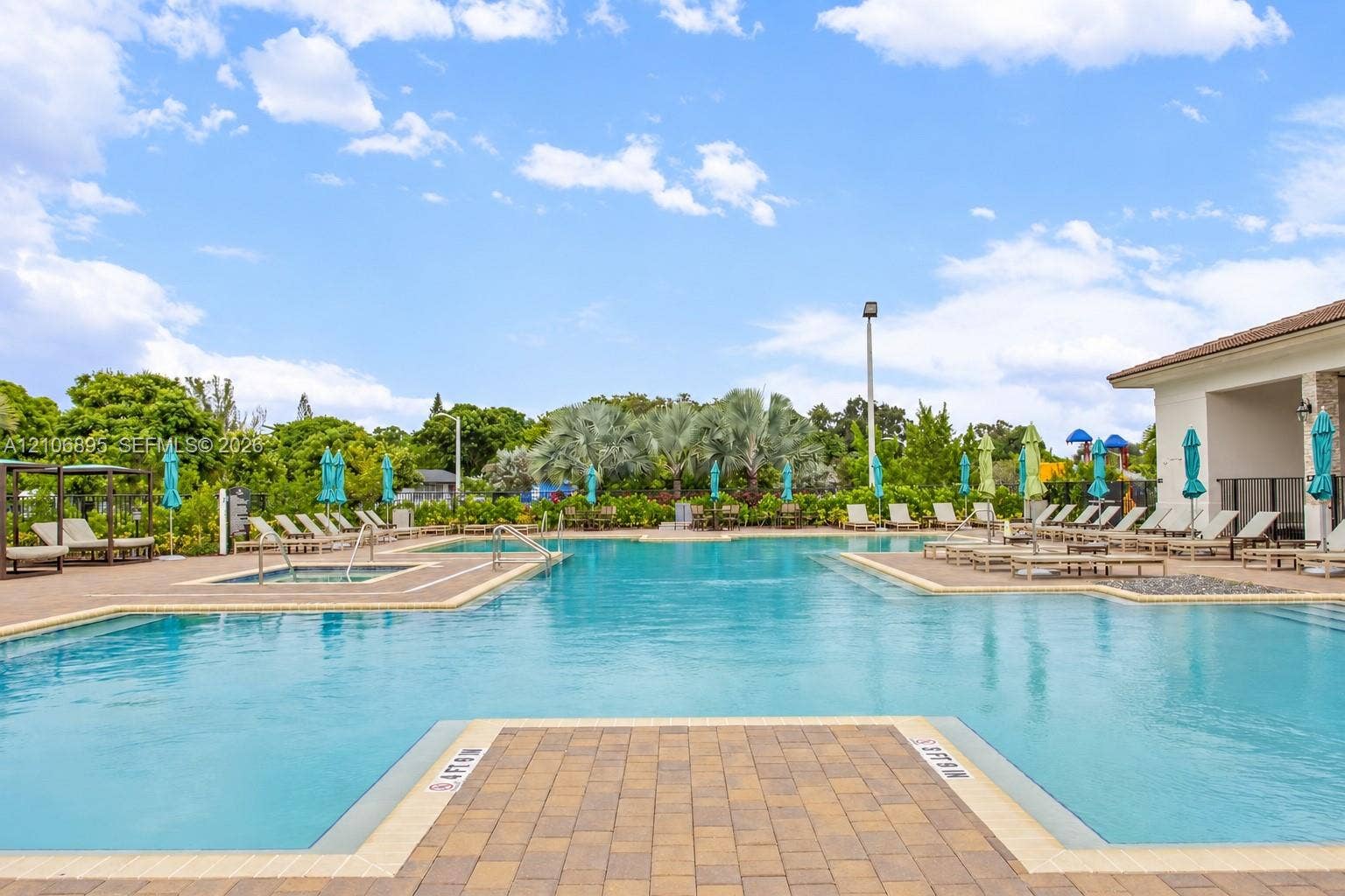 Swimming pool with integrated spa, surrounded by expansive paver decking and mature landscaping